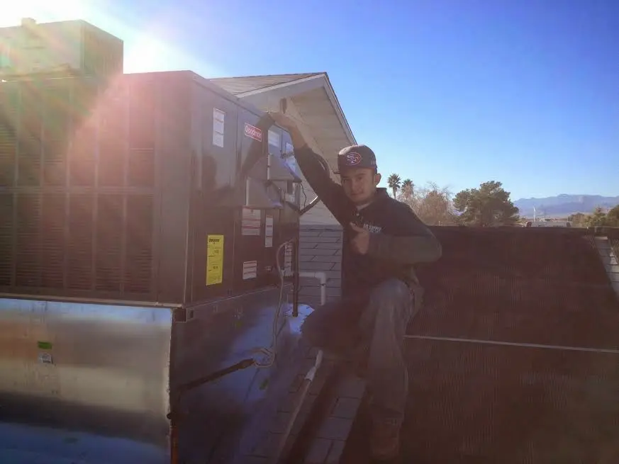 HVAC technician performing AC Tune-Up on a rooftop unit in Lake Geneva